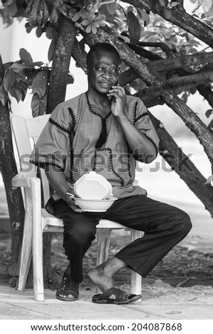ACCARA, GHANA - MAR 3, 2012: Unidentified Ghanaian man sits on a chair in black and white. People of Ghana suffer of poverty due to the unstable economical situation