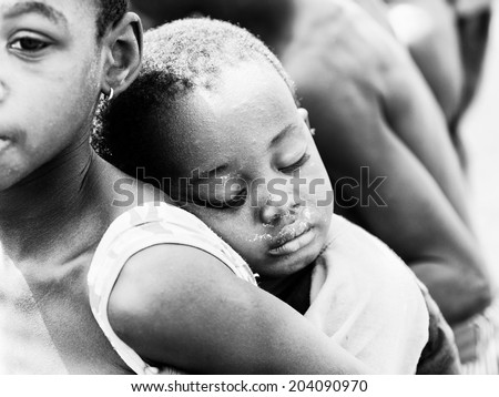 ACCARA, GHANA - MAR 6, 2012: Unidentified Ghanayan little boy sleeps on the back in black and white. People of Ghana suffer of poverty due to the unstable economical situation