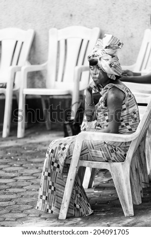 ACCARA, GHANA - MAR 3, 2012: Unidentified Ghanaian woman sits on a chair in black and white. People of Ghana suffer of poverty due to the unstable economical situation