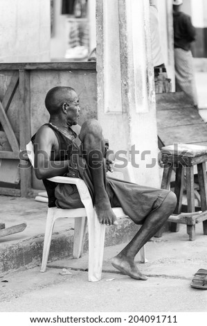 ACCARA, GHANA - MAR 2, 2012: Unidentified Ghanaian man sits on a chair in black and white. People of Ghana suffer of poverty due to the unstable economical situation