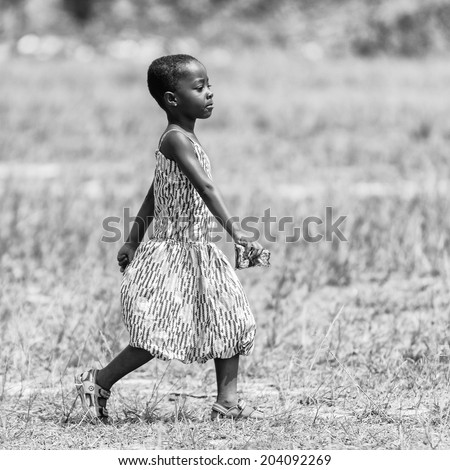 ACCARA, GHANA - MAR 2, 2012: Unidentified Ghanaian little girl runs heppily in the field in black and white. People of Ghana suffer of poverty due to the unstable economical situation