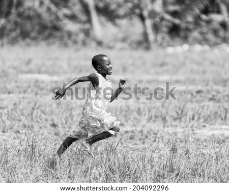 ACCARA, GHANA - MAR 2, 2012: Unidentified Ghanaian little girl runs heppily in the field in black and white. People of Ghana suffer of poverty due to the unstable economical situation