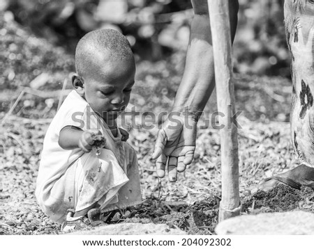 ACCARA, GHANA - MAR 3, 2012: Unidentified Ghanaian little boy helps his mother to work in the field in black and white. People of Ghana suffer of poverty due to the unstable economical situation