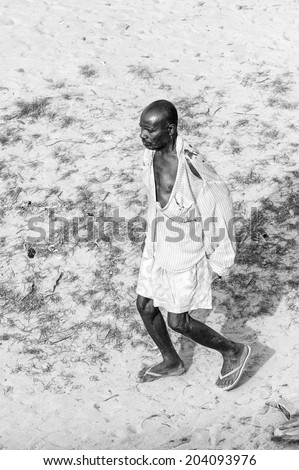ACCARA, GHANA - MAR 2, 2012: Unidentified Ghanaian man walks on a sand in black and white. People of Ghana suffer of poverty due to the unstable economical situation