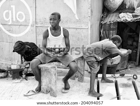 ACCARA, GHANA - MAR 2, 2012: Unidentified Ghanaian people sit in the street  in black and white. People of Ghana suffer of poverty due to the unstable economical situation