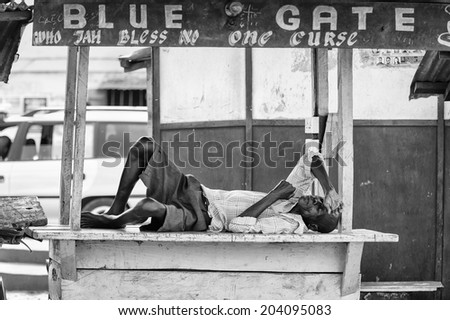 ACCARA, GHANA - MAR 2, 2012: Unidentified Ghanaian man sleeps on a bench in the street in black and white. People of Ghana suffer of poverty due to the unstable economical situation