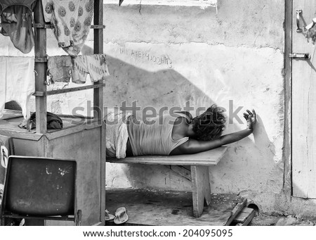 ACCARA, GHANA - MAR 2, 2012: Unidentified Ghanaian woman sleeps on a bench in black and white. People of Ghana suffer of poverty due to the unstable economical situation