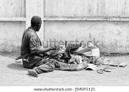 ACCARA, GHANA - MAR 2, 2012: Unidentified Ghanaian  man sits in the street in the street in black and white. People of Ghana suffer of poverty due to the unstable economical situation