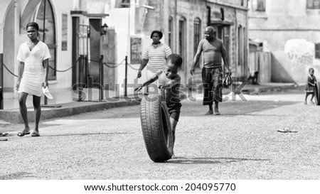 ACCARA, GHANA - MAR 2, 2012: Unidentified Ghanaian boy plays with a tyre in black and white. People of Ghana suffer of poverty due to the unstable economical situation