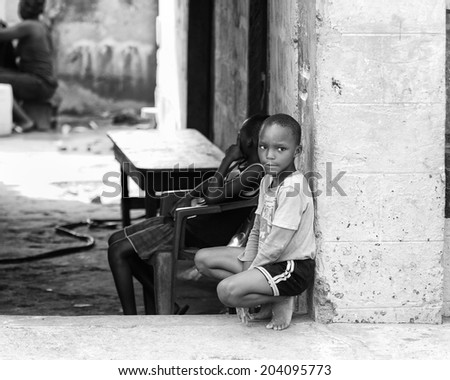ACCARA, GHANA - MAR 2, 2012: Unidentified Ghanaian boy sits near a wall in black and white. People of Ghana suffer of poverty due to the unstable economical situation