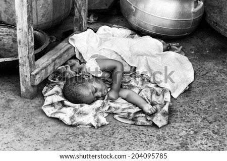 ACCARA, GHANA - MAR 2, 2012: Unidentified Ghanaian girk sleeps on the ground in black and white. Children of Ghana suffer of poverty due to the unstable economical situation