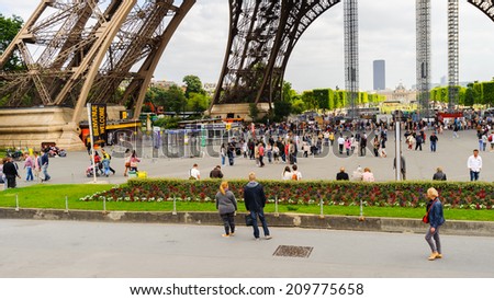 PARIS, FRANCE - JUN 17, 2014: Unidentified tourists walk near the Eiffel Tower in Paris, France. The Eiffel tower was created by Gustave Eiffel and the construction was completed in 1889