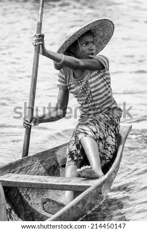 PORTO-NOVO, BENIN - MAR 9, 2012: Unidentified Beninese woman raws a green wooden boat. People of Benin suffer of poverty due to the difficult economic situation.