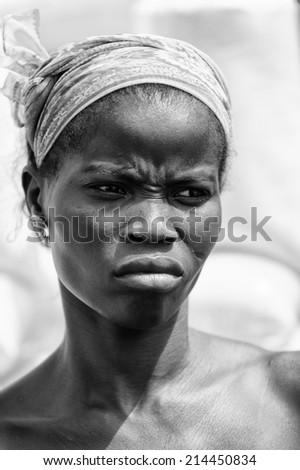 PORTO-NOVO, BENIN - MAR 8, 2012: Unidentified Beninese angry girl works at the market. People of Benin suffer of poverty due to the difficult economic situation.