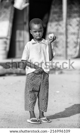 PORTO-NOVO, BENIN - MAR 9, 2012: Unidentified Beninese little boy with a apple at the market. People of Benin suffer of poverty due to the difficult economic situation.