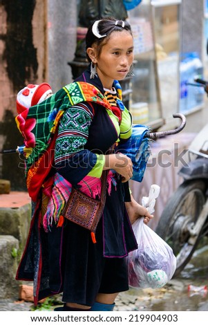 SAPA, VIETNAM - SEP 20, 2014: Unidentified Hmong woman in the Hmong traditional costume carries her liitle baby on her back. Hmong people is a minority ethnic group living in Sapa