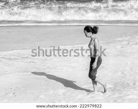 NHA TRANG, VIETMAN - SEP 22, 2014: Unidentified Vietnamese woman walks on a sand coast in Nha Trang, Vietnam. 86% of Vietnamese people belong to the Viet ethnic group