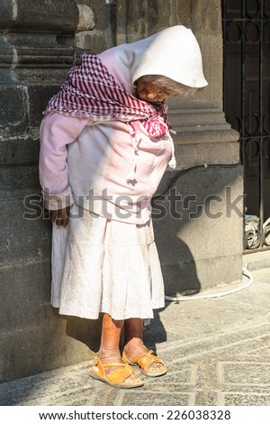 MEXICO CITY, MEXICO - DEC 29, 2011: Unidentified Mexican woman stays near a wall in the street. 60% of Mexican people belong to the Mestizo ethnic group