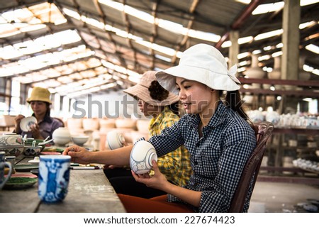 HANOI, VIETNAM - SEP 24, 2014: Unidentified Vietnamese woman draws on the ceramic dish in the ceramic workshop. Ceramic art is very popular in Asian culture