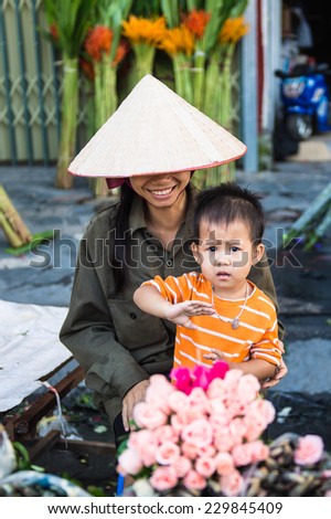 HANOI, VIETNAM - SEP 23. 2014: Unidentified woman and her chlld works at the flower market in Hanoi, Vietnam. Flower market in Hanoi is one of the largest flower markets in Vietnam