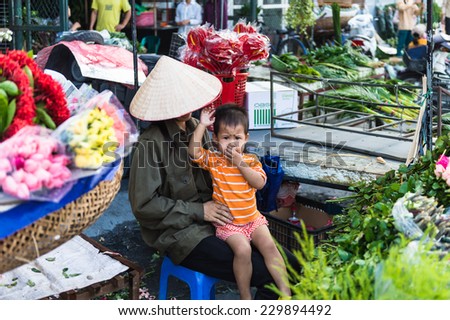 HANOI, VIETNAM - SEP 23. 2014: Unidentified woman and her chlld works at the flower market in Hanoi, Vietnam. Flower market in Hanoi is one of the largest flower markets in Vietnam