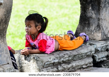 ANGKOR THOM, CAMBODIA - SEP 27, 2014: Unidentified girl lays at one of the temples of the Angkor Thom. Angkor Thom was the last capital city of the Khmer empire