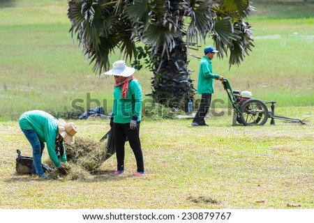 ANGKOR THOM, CAMBODIA - SEP 27, 2014: Unidentified Khmer woman cleans the territory of the Angkor Thom. 90% of Cambodian people belong to Khmer etnic group