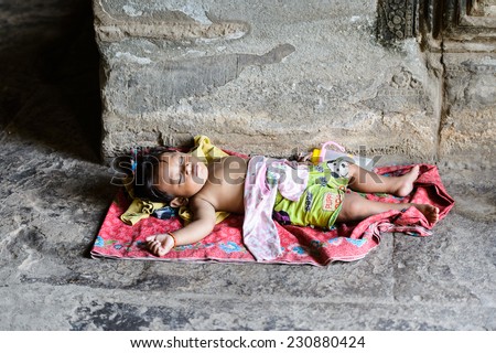 ANGKOR THOM, CAMBODIA - SEP 27, 2014: Unidentified Khmer girl sleeps at one of the temples of the Angkor Thom. Angkor Thom was the last capital city of the Khmer empire