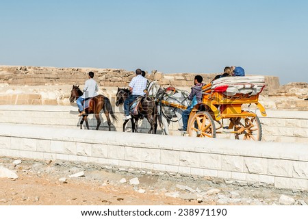 GIZA, EGYPT - NOV 23, 2014: Unidentified people ride horse carriage at Giza Necropolis, Egypt. UNESCO World Heritage