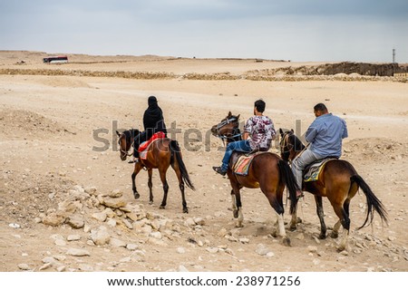 GIZA, EGYPT - NOV 23, 2014: Unidentified Egyptian people ride horses in Giza Necropolis, Egypt. UNESCO World Heritage