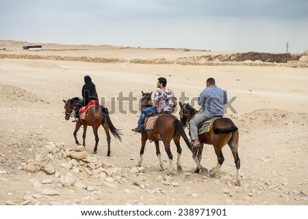 GIZA, EGYPT - NOV 23, 2014: Unidentified Egyptian people ride horses in Giza Necropolis, Egypt. UNESCO World Heritage