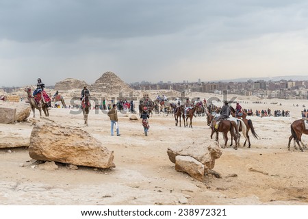 GIZA, EGYPT - NOV 23, 2014: Unidentified tourists and local horse and camel riders in Giza Necropolis, Egypt. UNESCO World Heritage