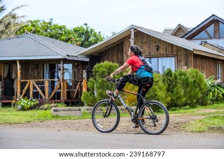 EASTER ISLAND, CHILE - NOV 10, 2014: Unidentified Chilean girl rides a bycicle on the Easter Island, Chile. Easter Island is a UNESCO World Heritage