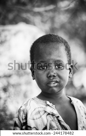 BANJUL, GAMBIA - MAR 14, 2013: Unidentified Gambian little boy in blue and white clothes walks in the street in Gambia, Mar 14, 2013. Major ethnic group in Gambia is the Mandinka - 42%