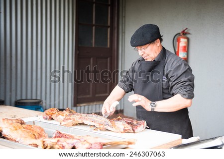 PATAGONIA, CHILE - NOV 6, 2014:  Unidentified Chilean man preapares a traditional national food of Chile Asado. Chilean people are of mixed Spanish and Amerindian descent