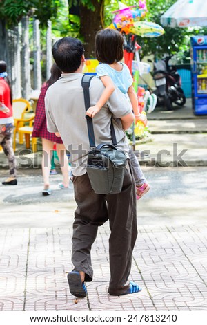 HO CHI MINH, VIETNAM - OCT 6, 2014: Unidentified Vietnamese man carries his little daugher. 90% of Vietnamese people belong to the Viet ethnic group