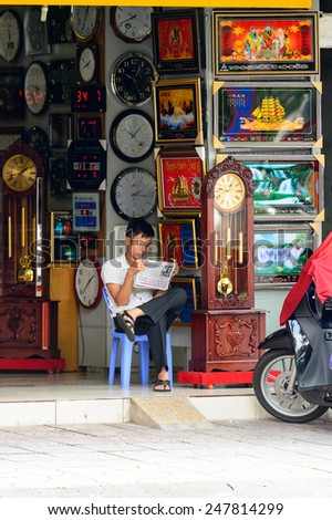 HO CHI MINH, VIETNAM - SEP 20, 2014: Unidentified Vietnamese man reads newspaper in the street in the street. 90% of Vietnamese people belong to the Viet ethnic group