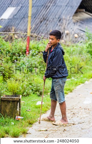 TA PHIN, LAO CAI, VIETNAM - SEP 21, 2014:  Unidentified Red Daoboy walks with a stick. Red Dao is one of the minority ethnic groups in Vietnam