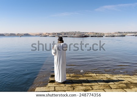 ASWAN, EGYPT - DEC 2, 2014: Unidentified Egyptian man on the coast of the NIle. 90% of Egyptian people are Muslim