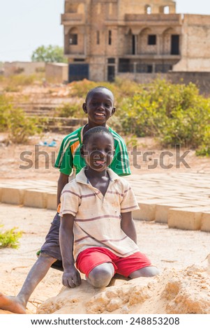 LOUGA, SENEGAL - MAR 15, 2013: Unidentified Senegalese boys play over the sand and smile Children in Senegal suffer of poverty due to the unstable economic situation