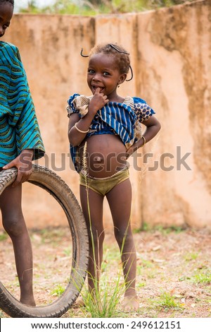 KARA, TOGO - MAR 9, 2013: Unidentified Togolese little girl stays and thinks in the street. Children in Togo suffer of poverty due to the unstable econimic situation