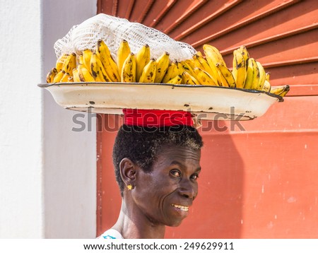 KARA, TOGO - MAR 9, 2013: Unidentified Togolese smiling woman carries a tray with bananas. People in Togo suffer of poverty due to the unstable econimic situation