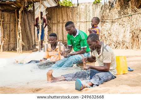 KARA, TOGO - MAR 9, 2013: Unidentified Togolese men sew the fish net for fishing. People in Togo suffer of poverty due to the unstable econimic situation