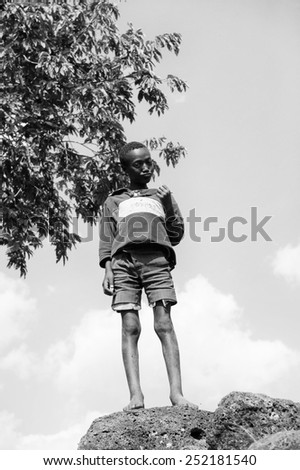 OMO, ETHIOPIA - SEPTEMBER 20, 2011: Unidentified Ethiopian thin boy stays on the stone. People in Ethiopia suffer of poverty due to the unstable situation