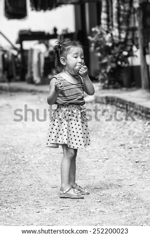 LUANG PRABANG, LAOS - SEP 25, 2014: Unidentified Lao little girl eats a candy. 55% of Laos people belong to the Lao ethnic group