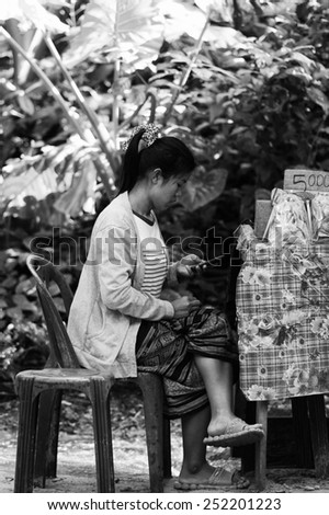 LUANG PRABANG, LAOS - SEP 25, 2014: Unidentified Lao woman plays phone. 55% of Laos people belong to the Lao ethnic group