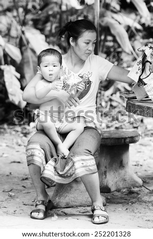 LUANG PRABANG, LAOS - SEP 25, 2014: Unidentified Lao woman and her little sun. 55% of Laos people belong to the Lao ethnic group