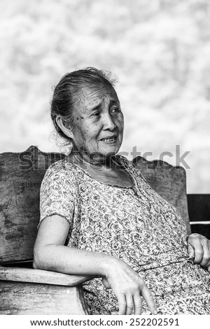 LUANG PRABANG, LAOS - SEP 25, 2014: Unidentified Lao woman sits on a bench bear the Mekong river. 55% of Laos people belong to the Lao ethnic group