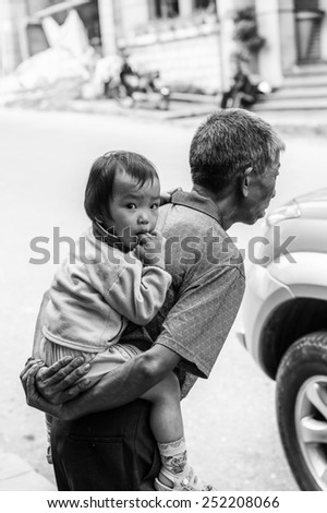 SAPA, VIETNAM - SEP 22, 2014: Unidentified Hmong little girl on her father back in Sapa. Hmong is on of the minority eethnic group in Vietnam