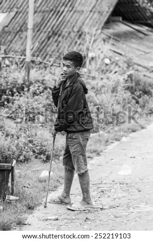 TA PHIN, LAO CAI, VIETNAM - SEP 21, 2014:  Unidentified Red Daoboy walks with a stick. Red Dao is one of the minority ethnic groups in Vietnam